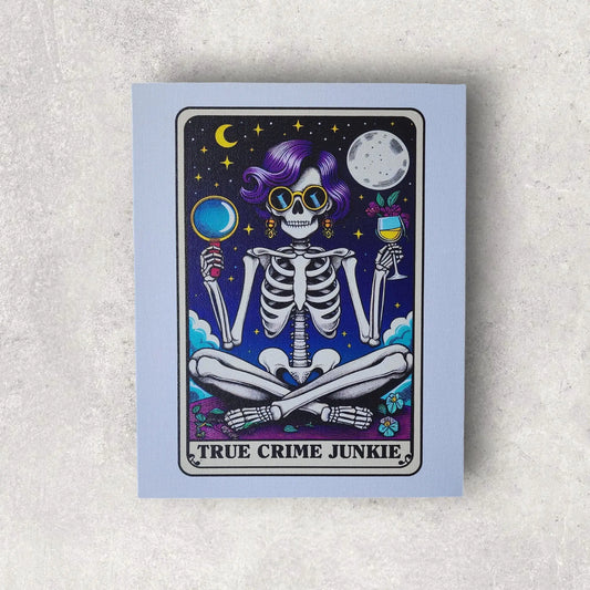 The True Crime Junkie Funny 8x10 Canvas Sign from Mirabilia Boutique features an illustration of a skeleton with purple hair and dark sunglasses. The whimsical scene shows the skeleton holding a magnifying glass in one hand and a glass of wine in the other, set against a starry night backdrop with both a crescent moon and a full moon. The text reads "TRUE CRIME JUNKIE.
