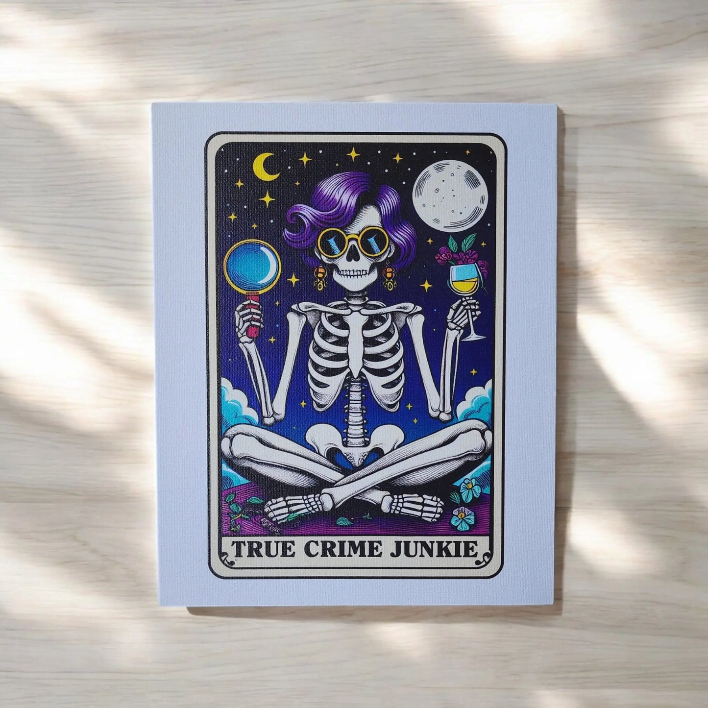 The *True Crime Junkie Funny 8x10 Canvas Sign* by Mirabilia Boutique features an illustration of a skeleton with purple hair, sunglasses, and gold earrings, sitting cross-legged against a dark starry background. The skeleton holds a magnifying glass in one hand and a wine glass in the other. The text "TRUE CRIME JUNKIE" is displayed at the bottom, making it perfect for true crime decor.