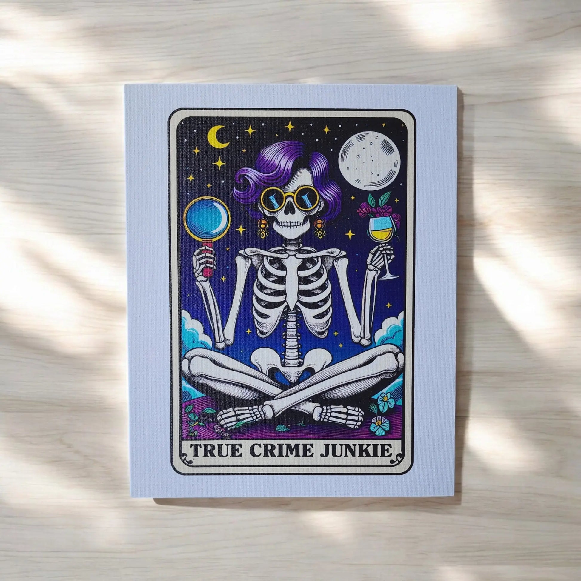 The *True Crime Junkie Funny 8x10 Canvas Sign* by Mirabilia Boutique features an illustration of a skeleton with purple hair, sunglasses, and gold earrings, sitting cross-legged against a dark starry background. The skeleton holds a magnifying glass in one hand and a wine glass in the other. The text "TRUE CRIME JUNKIE" is displayed at the bottom, making it perfect for true crime decor.