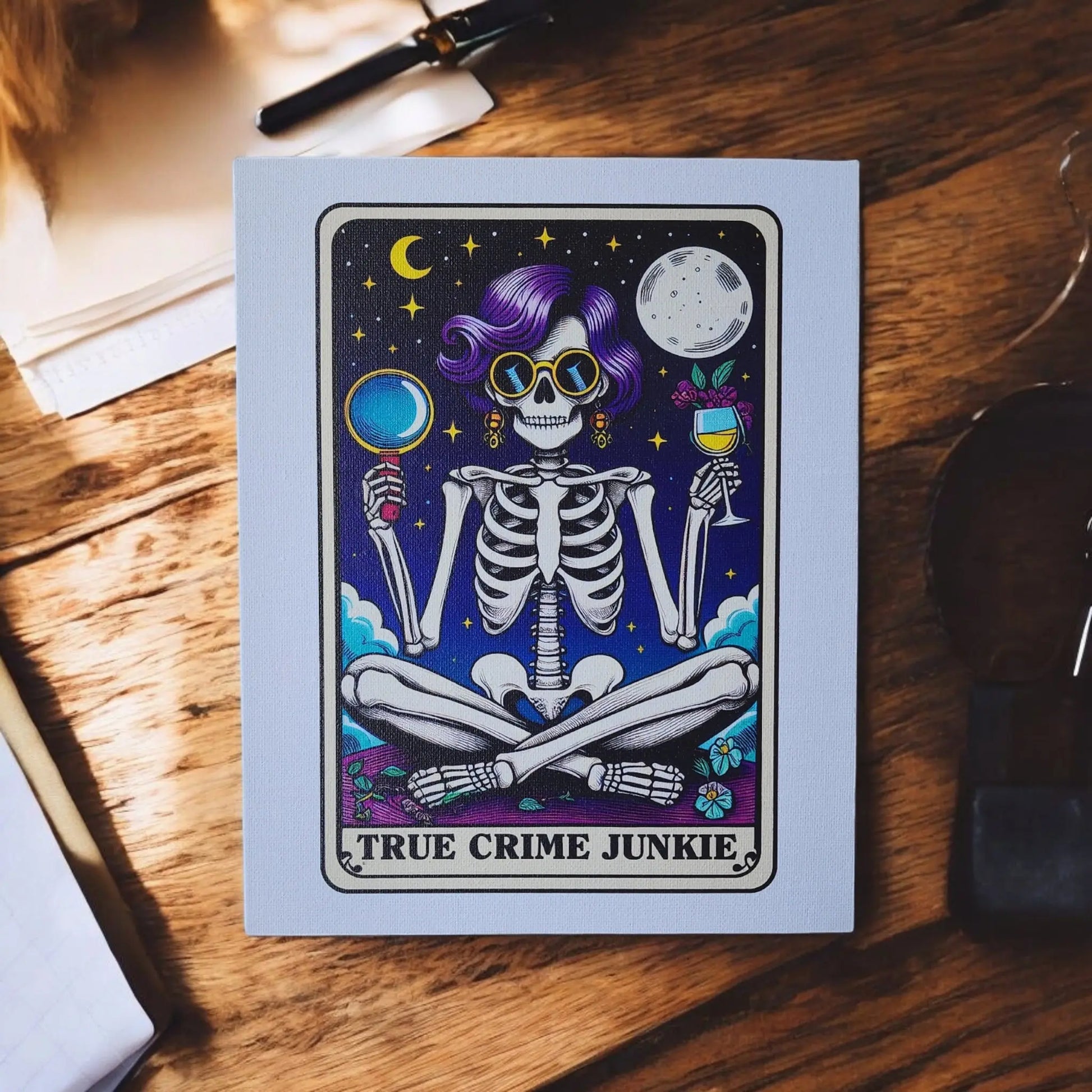 A canvas sign from Mirabilia Boutique named "True Crime Junkie" features a vibrant illustration of a skeleton with purple hair, sunglasses, holding a magnifying glass and a glass of wine. Celestial elements like stars and the moon adorn the background. Measuring 8x10 inches, this canvas is ideal for true crime decor enthusiasts!