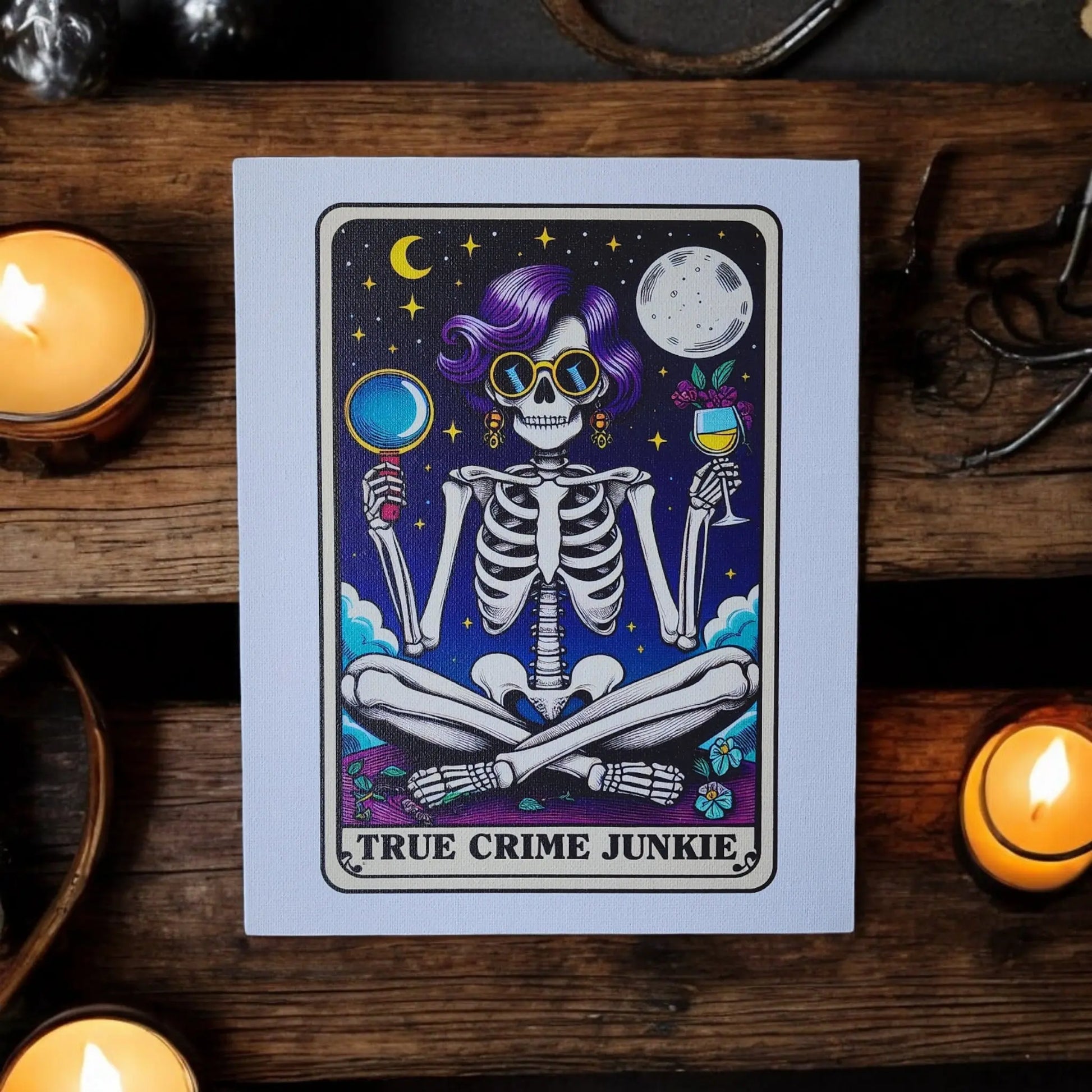 The "True Crime Junkie Funny 8x10 Canvas Sign" from Mirabilia Boutique showcases a skeleton with purple hair and sunglasses sitting cross-legged. The skeleton holds a magnifying glass and a wine glass against a starry night sky backdrop, while candles frame the piece perfectly for your true crime decor needs.