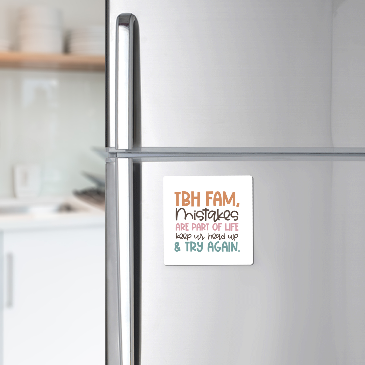 A Mirabilia Boutique Growth Mindset Teacher Magnet with the quote "Try Again" is displayed on a refrigerator. The magnet reads, "TBH FAM, Mistakes are part of life. Keep ur head up & try again." Kitchen shelves and dishes appear in the background.