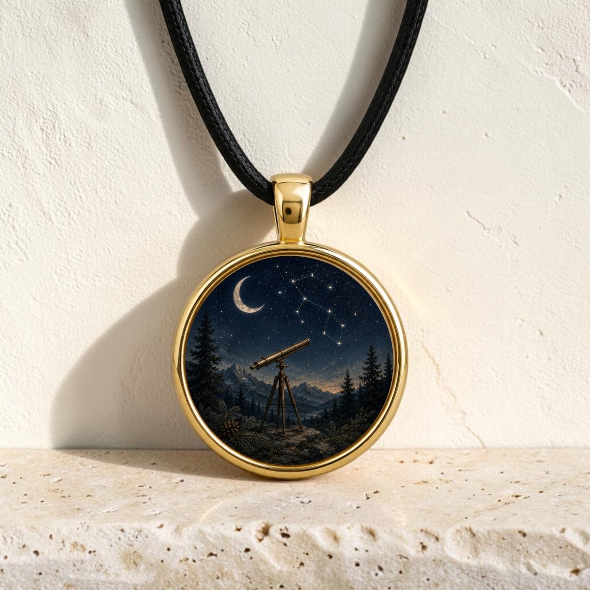 Introducing the Under the Constellations | Story Pendant Necklace by Mirabilia Boutique—a gold necklace adorned with an intricate illustration of a telescope beneath a starry night sky, crescent moon, and sparkling constellation, all surrounded by trees and mountains. This enchanting piece of stargazing jewelry is beautifully displayed against a light textured background.