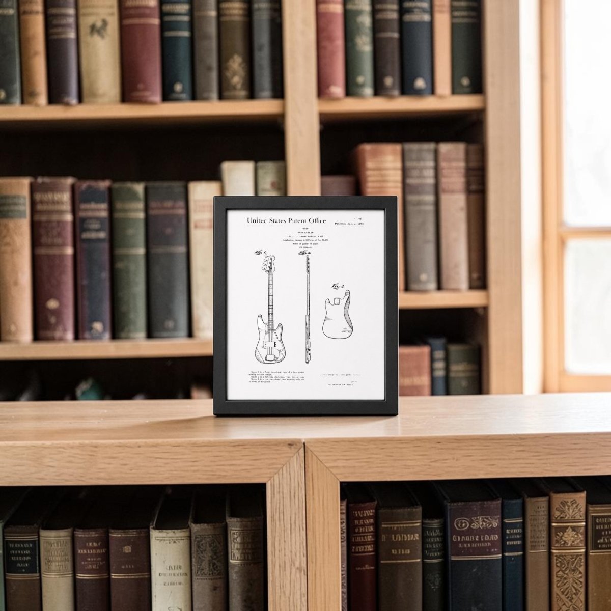The Mirabilia Boutique Bass Guitar Patent Print on Metal (8x10) is displayed on a bookshelf with old books, sunlight streaming in—an ideal wall art piece for music lovers’ decor.