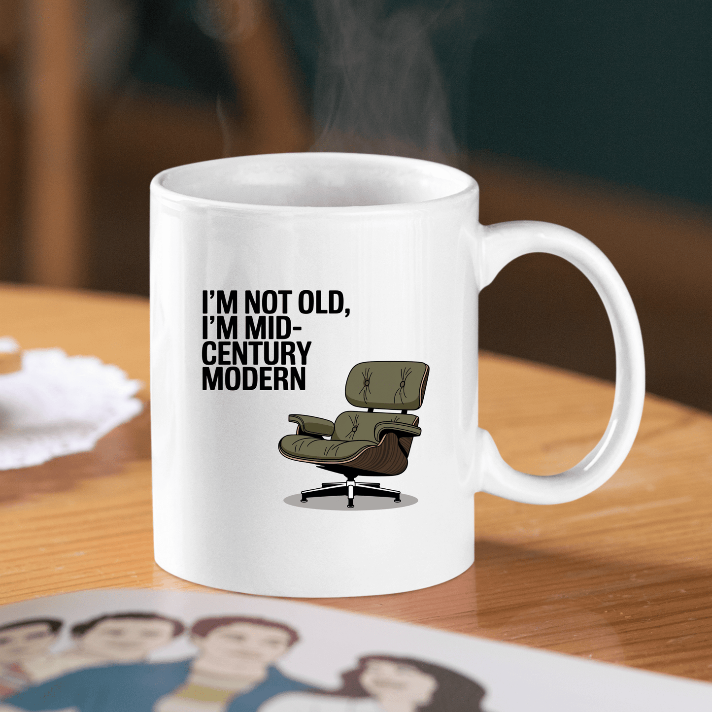 The Mirabilia Boutique Mid-Century Modern Mug with Retro Humor is a white ceramic mug featuring a green lounge chair and the phrase “I’M NOT OLD, I’M MID-CENTURY MODERN.” Perfect for adding retro charm to your coffee break.