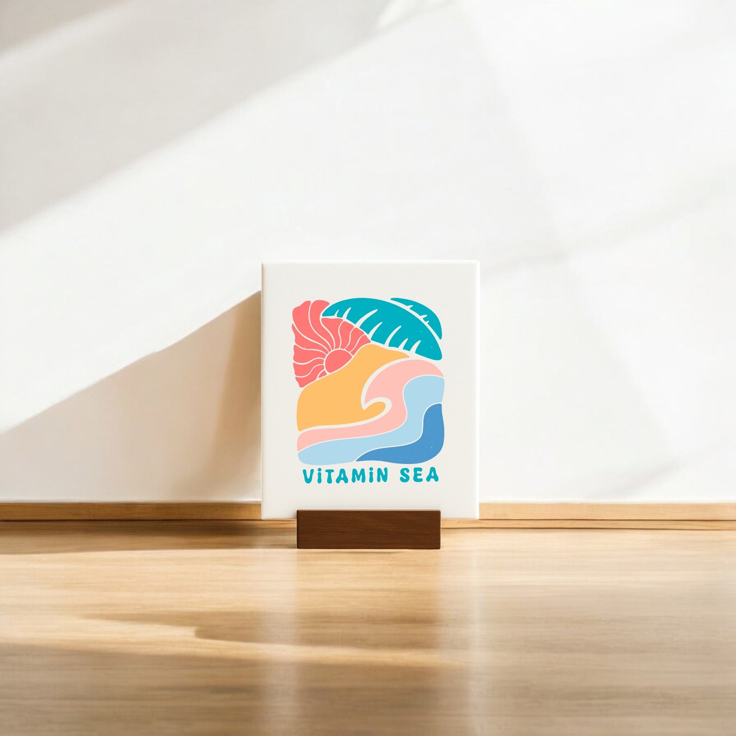 The Mirabilia Boutique Vitamin Sea Mini Canvas Sign – 4x6 Coastal Decor features colorful abstract shapes and "VITAMIN SEA" text on a wooden holder, adding a cheerful, beach-inspired touch to your space. Perfect for sunlit rooms or coastal-themed decor.