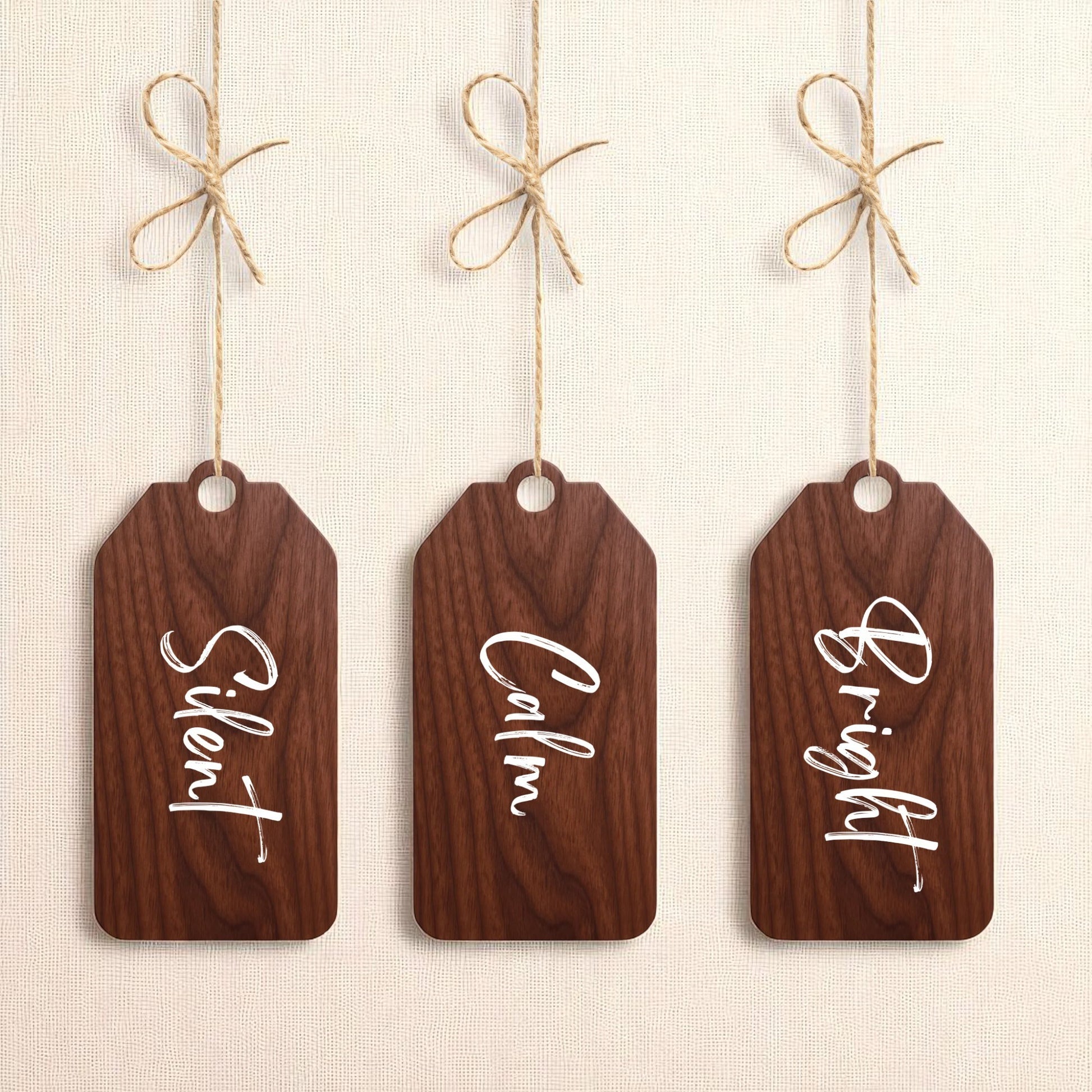 The Mirabilia Boutique Walnut Holiday Tags Set includes three minimalist walnut Christmas ornaments labeled “Silent,” “Calm,” and “Bright” for a charming holiday touch.