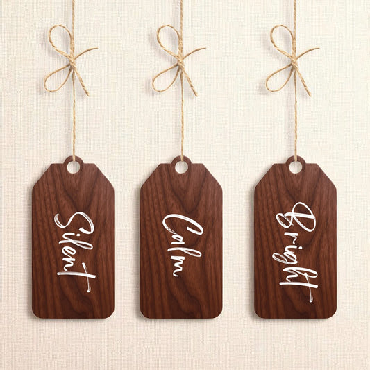 The Mirabilia Boutique Walnut Holiday Tags Set includes three minimalist walnut Christmas ornaments labeled “Silent,” “Calm,” and “Bright” for a charming holiday touch.