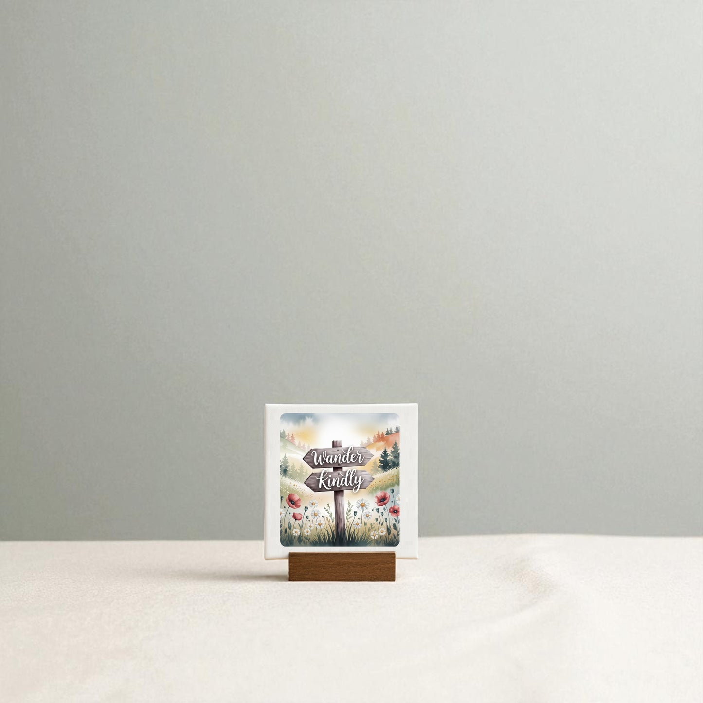 A small card on a wooden stand reads "Wander Kindly" by Mirabilia Boutique, featuring a nature-inspired floral design—perfect mini shelf decor—displayed on a beige surface with a light gray background.