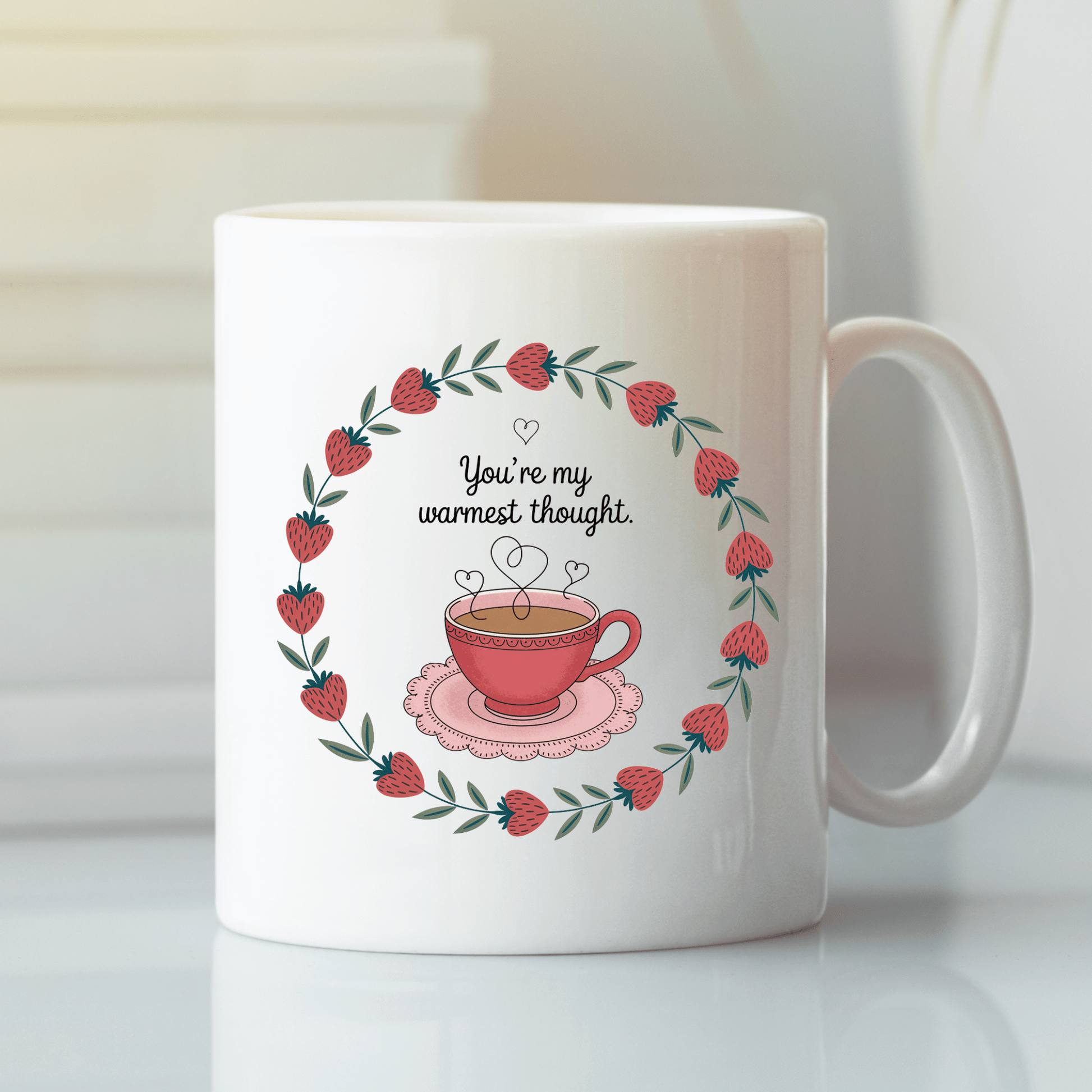 The Warmest Thought Mug – Sweet Teacup Gift Mug by Mirabilia Boutique features a red teacup inside a strawberry wreath with "You're my warmest thought" in cursive, set on a light surface with a soft background.