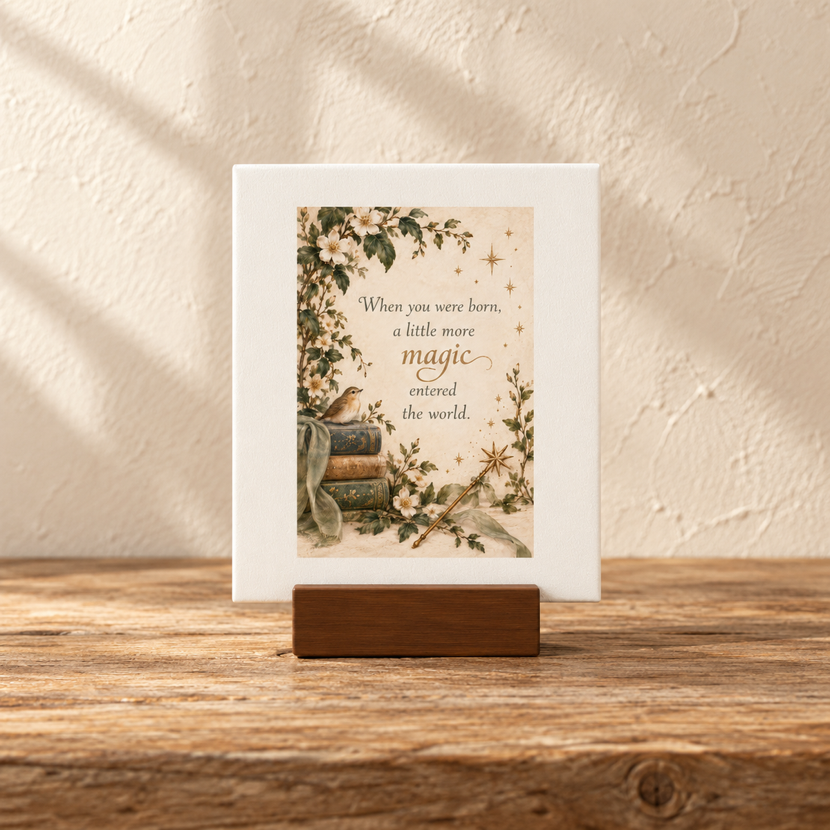 A Little More Magic 4x6 Mini Friend Gift Sign by Mirabilia Boutique (Moon & Moss Collection) is shown on a wooden stand, featuring charming illustrations of flowers, books, and a bird along with the heartfelt message: “When you were born, a little more magic entered the world.” Set against a textured cream background, this enchanting scene evokes woodland whimsy and makes for a thoughtful gift.