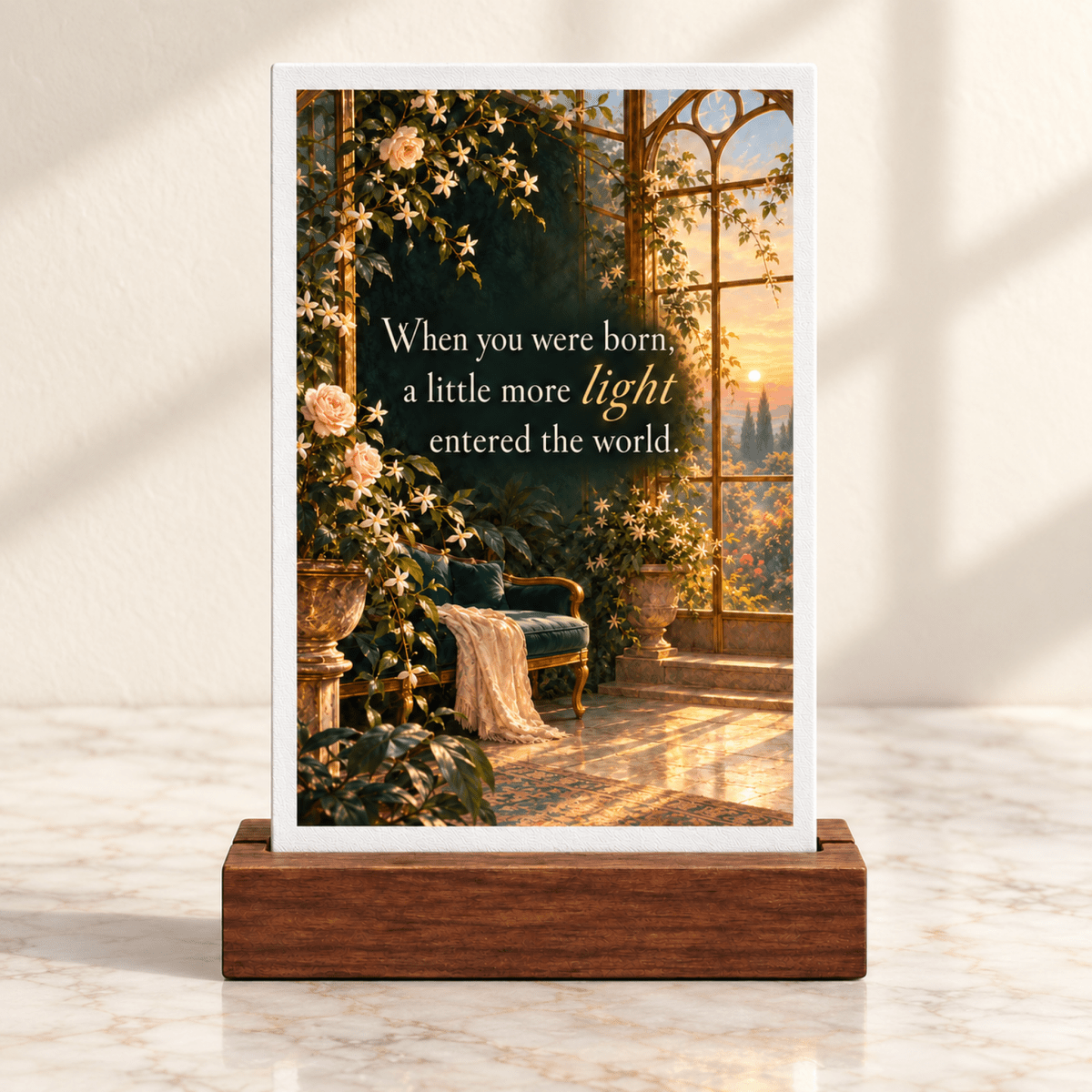 When You Were Born Light Mini Sign | Gilded Reverie displayed in a wooden stand, featuring a rectangular illustration of a sunlit sunroom with roses and the text, “When you were born, a little more light entered the world.”