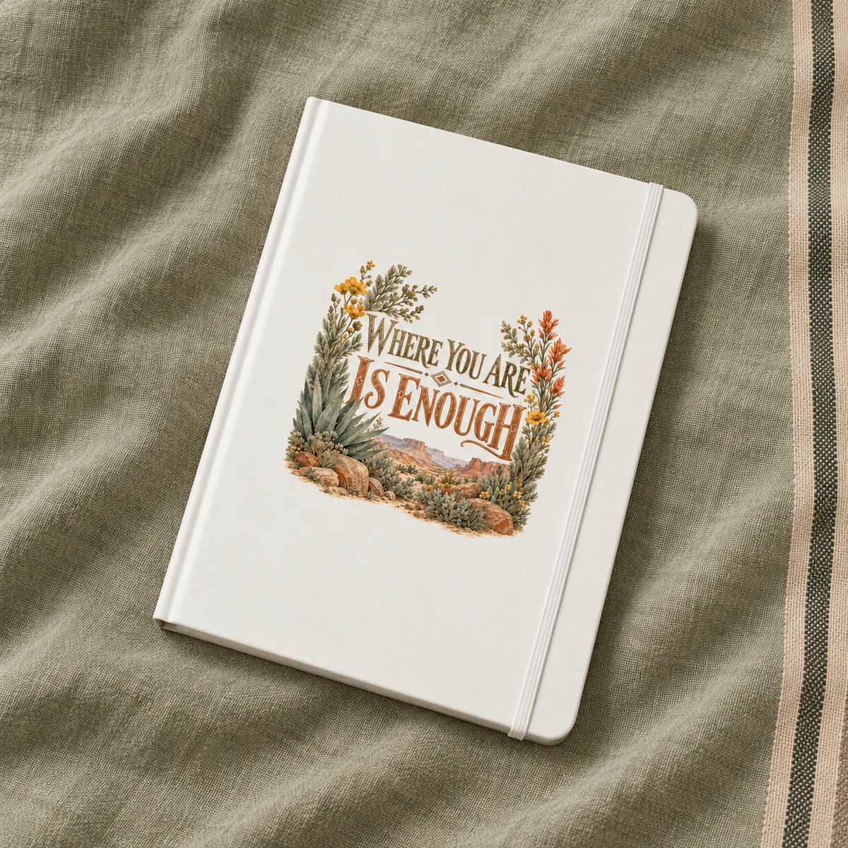 The Where You Are Is Enough A5 Lined Journal | Sage & Stone by Mirabilia Boutique features a white cover with floral art and the quote “Where you are is enough,” displayed on textured beige fabric.