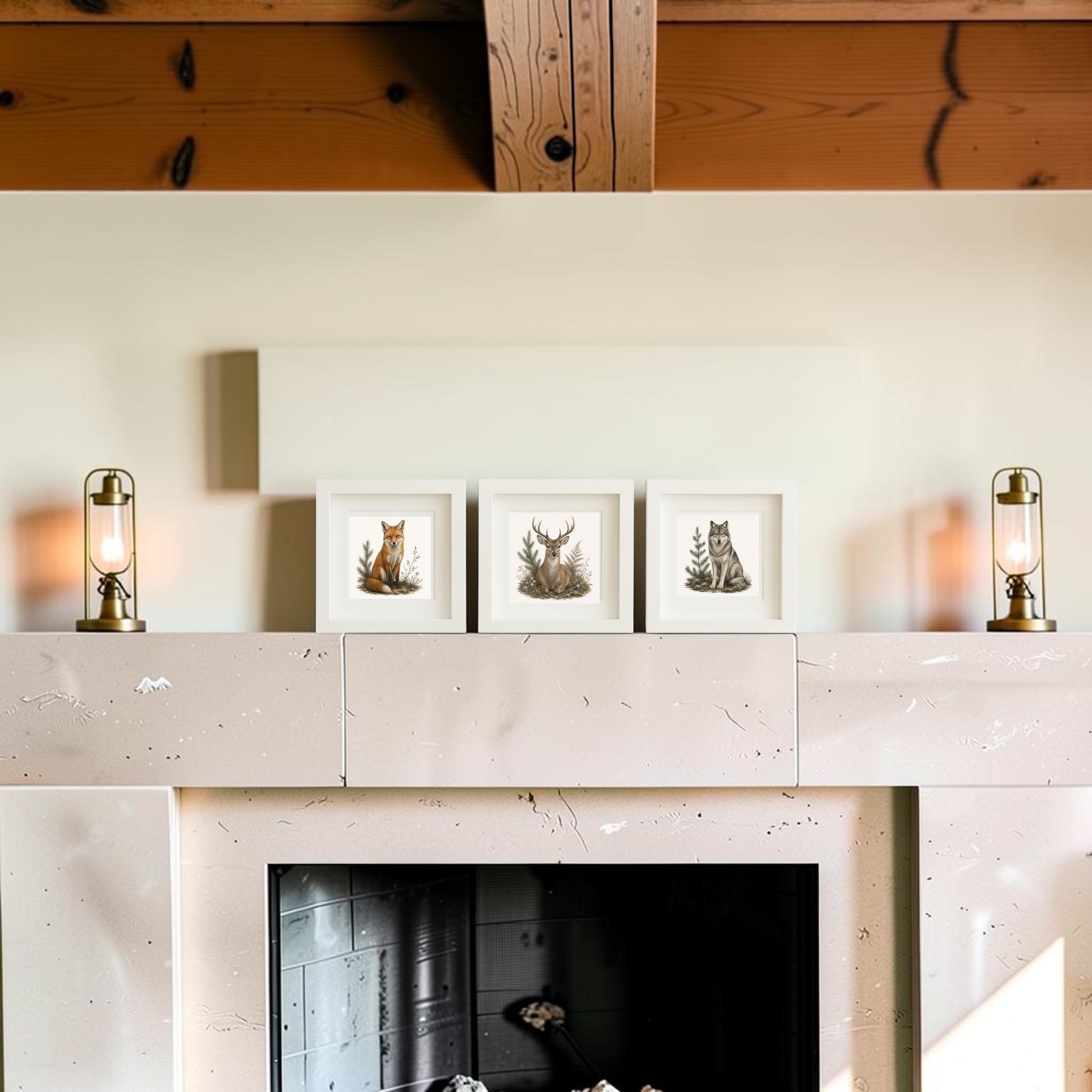 A stone fireplace mantel features the Winter Vigil Wildlife Shadowbox Trio by Mirabilia Boutique—three 5x5 framed illustrations of a fox, deer, and wolf—nestled between two brass lantern lamps against a neutral wall with exposed wooden beams above. This arrangement infuses your living space with the enchanting charm of winter wildlife art and pairs beautifully with pieces from the Star & Solstice Collection.