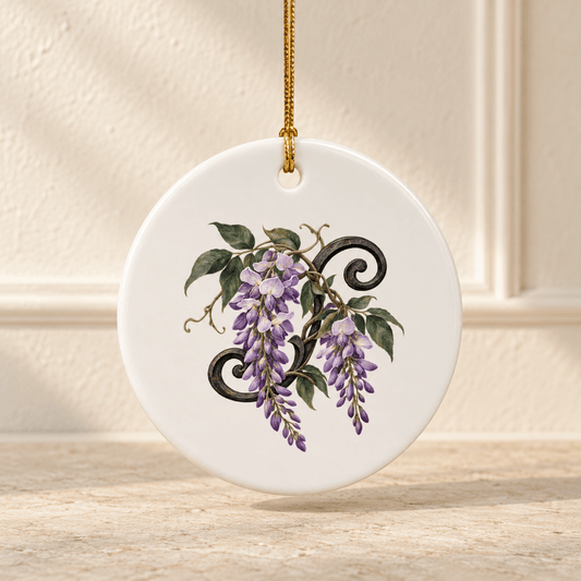 Wisteria at Blue Hour Ornament by Mirabilia Boutique, a round white ceramic ornament hanging by a gold string featuring a painting of purple wisteria blossoms draped over a black iron scrollwork design.