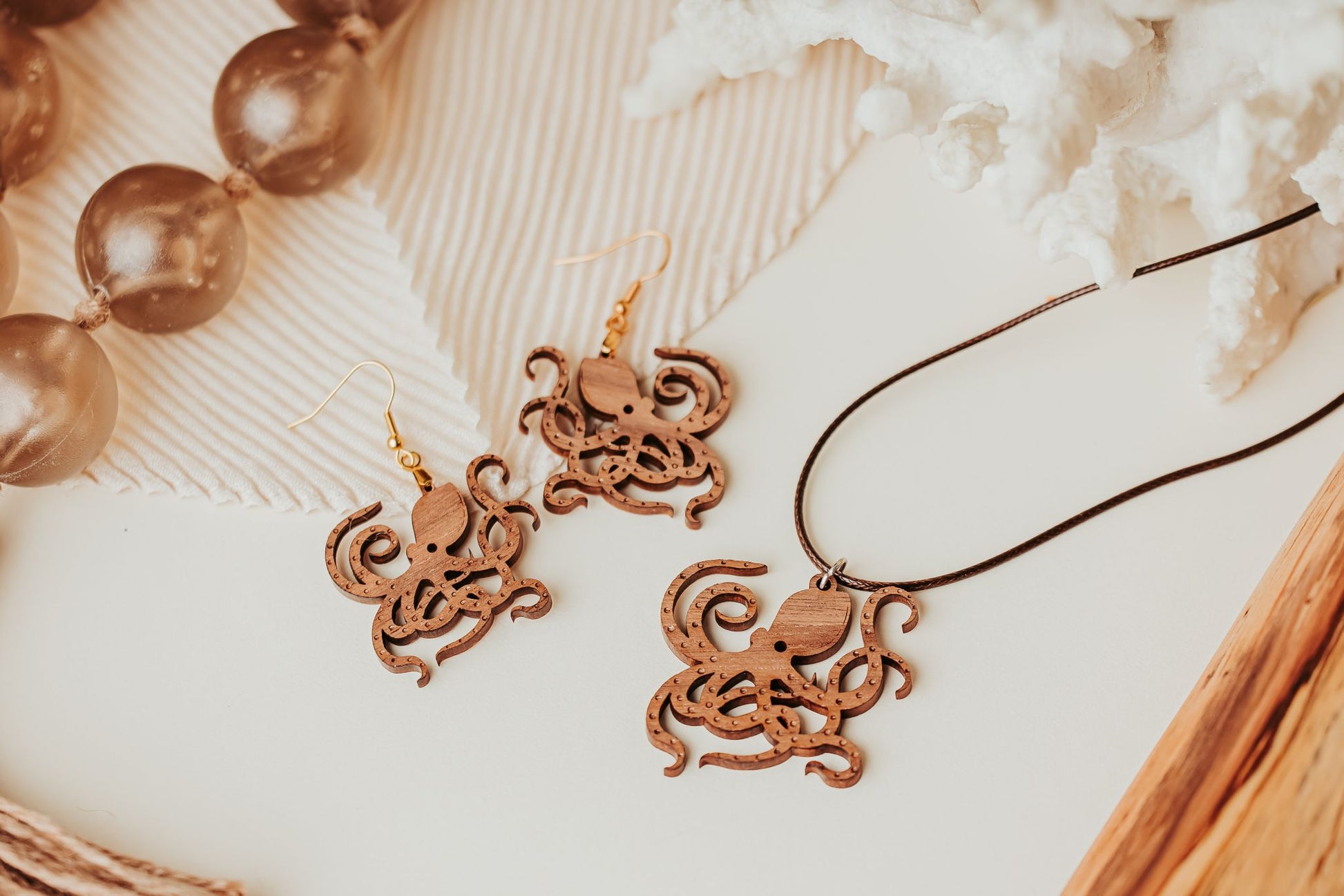 Mirabilia Boutique’s Octopus Earrings – Laser Cut Wood Ocean Jewelry Gift for Nature or Sea Life Lovers – are displayed with a matching pendant, translucent beads, and white coral on a light surface.