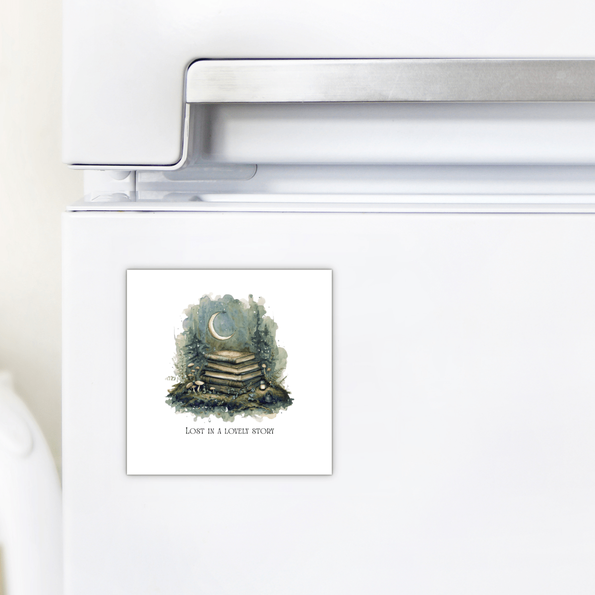 A Mirabilia Boutique “Lost in a Lovely Story Book Lover Magnet” is displayed on a white refrigerator, featuring a handcrafted design with a stack of books topped by a crescent moon. The magnet reads "Lost in a lovely story," making it an enchanting literary gift for anyone who cherishes the magic of reading.
