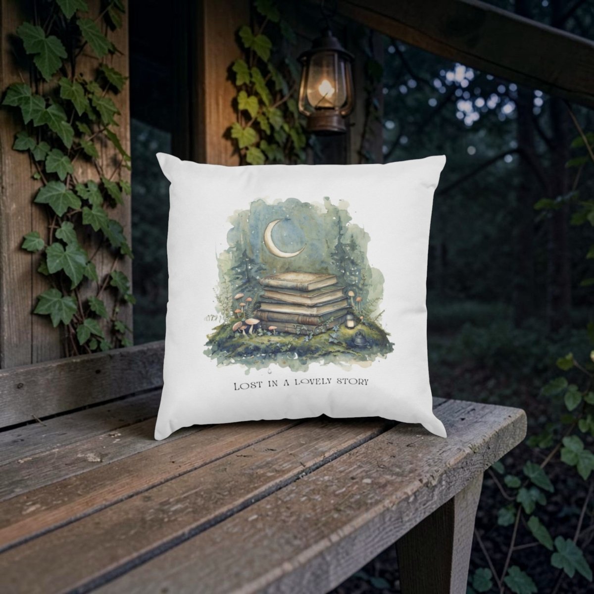 A white Lost in a Lovely Story Throw Pillow by Mirabilia Boutique, featuring an illustration of stacked books, mushrooms, and a crescent moon alongside the text "LOST IN A LOVELY STORY," sits on a wooden bench outdoors near a lantern, with ivy climbing up a wooden wall in the background. Perfect for cottagecore decor.