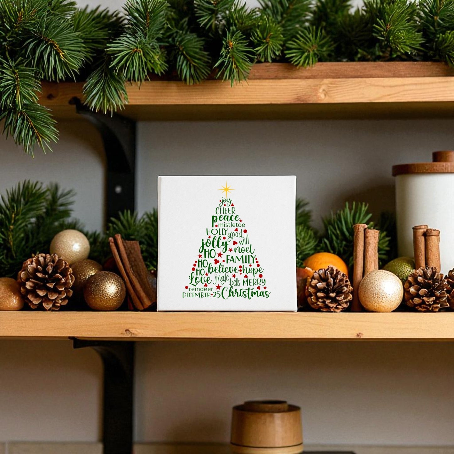 A wooden shelf displays evergreen branches, gold ornaments, cinnamon sticks, and a Mirabilia Boutique Word Art Christmas Tree Canvas 8x8—a festive wall art piece shaped by holiday words for charming Christmas decor.