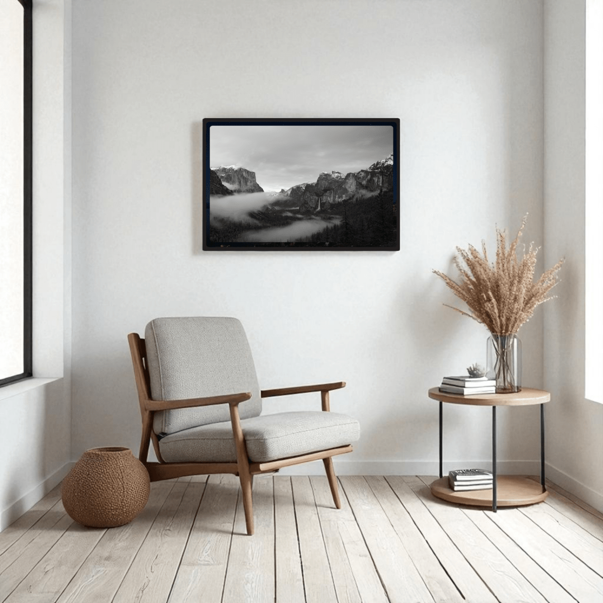 A modern, minimal living room with a light gray armchair, side table with dried pampas grass, woven basket, and Mirabilia Boutique’s Yosemite Valley Black & White Fine Art | Framed Art Print displayed above.