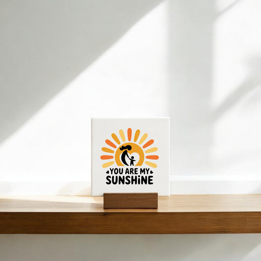 The You Are My Sunshine Mini Sign – Mom & Child Canvas from Mirabilia Boutique features a cheerful sun and sweet message, making it a perfect Mother’s Day gift. Sunlight highlights the simple illustration of an adult holding a child.