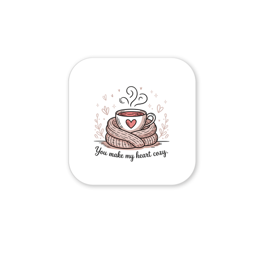 The Cozy Heart Magnet by Mirabilia Boutique features a steaming cup with a heart design, wrapped in a scarf and surrounded by hearts, with the text "You Make My Heart Cozy." A charming romantic gift for any cocoa lover.