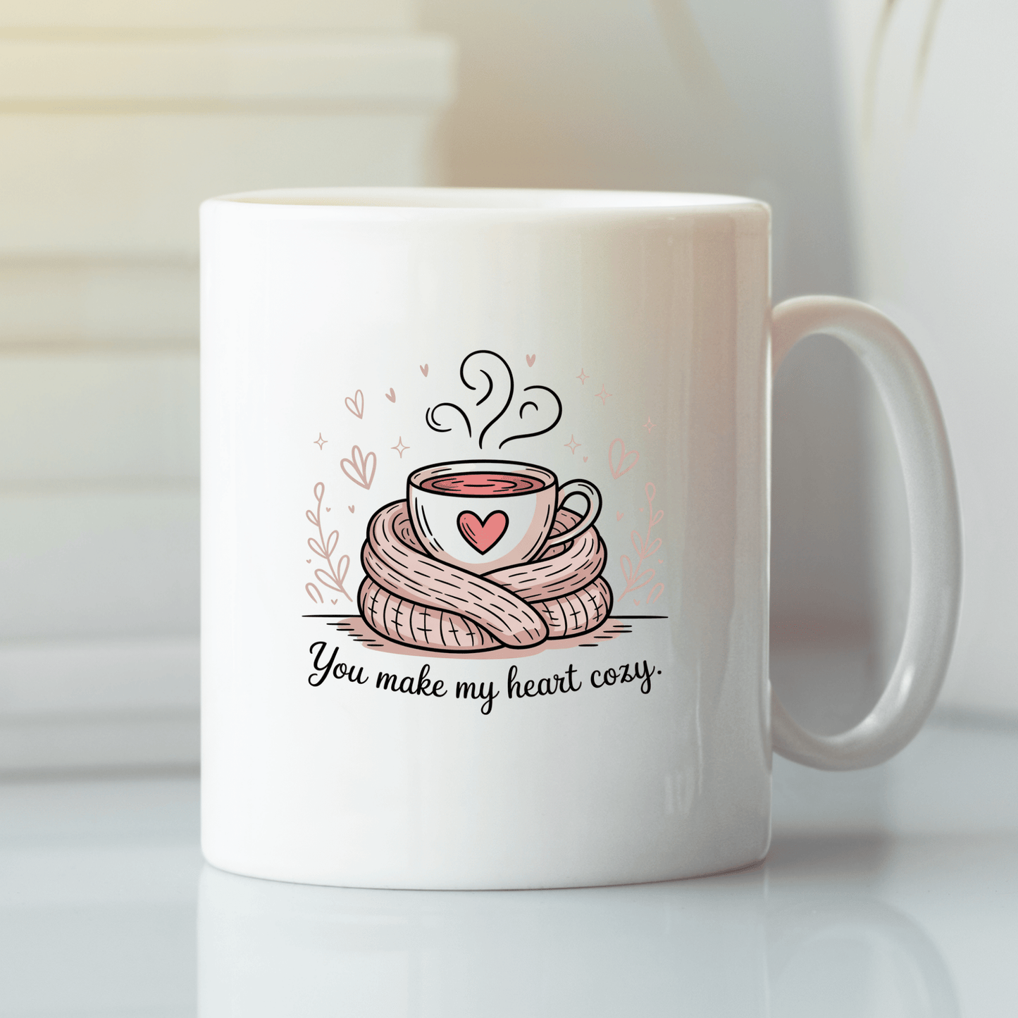 The "You Make My Heart Cozy Mug" by Mirabilia Boutique features a white mug with a steaming cup wrapped in a scarf and pink hearts, plus "You make my heart cozy" text—a cute Valentine’s Day gift for coffee lovers.