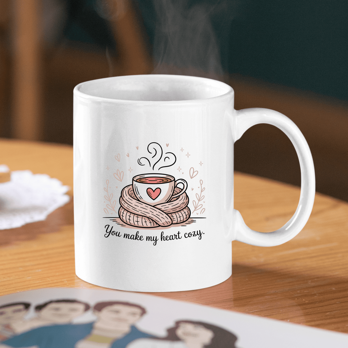 The "You Make My Heart Cozy Mug" by Mirabilia Boutique features a white design with a steaming cup in a scarf surrounded by hearts and the text "You make my heart cozy." A cute coffee lover gift, perfect for Valentine’s Day.