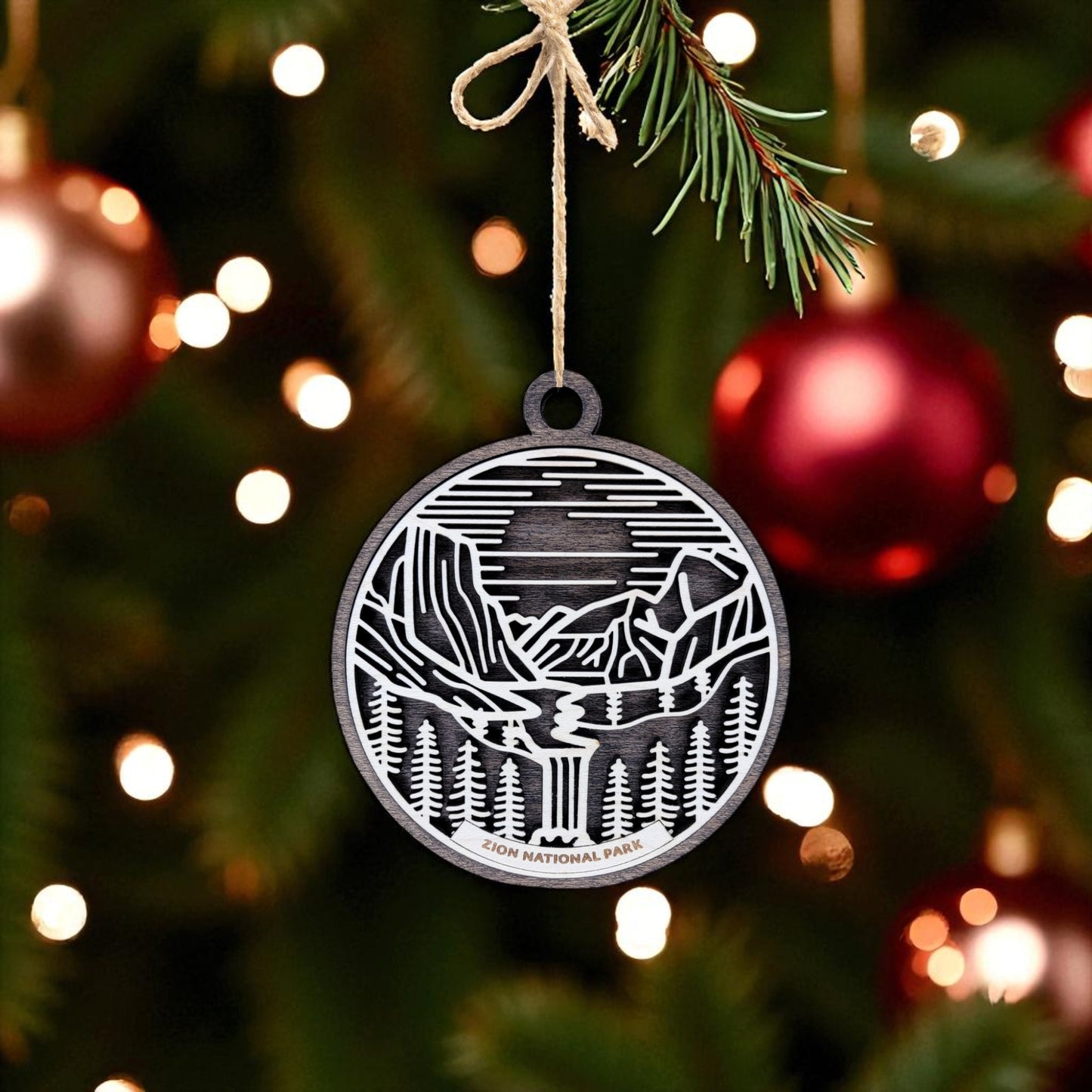 The Mirabilia Boutique Zion National Park Ornament is a handcrafted wooden keepsake featuring a landscape design and "Zion National Park" text, perfect for hanging on your Christmas tree alongside festive baubles and string lights.